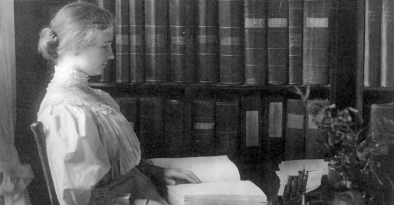 Helen Keller sitting reading a book in braille