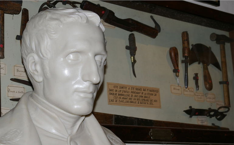 Bust of Louis Braille beside leathering equipment
