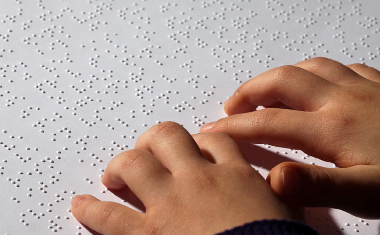 Close up of a child's hands while they read Braille