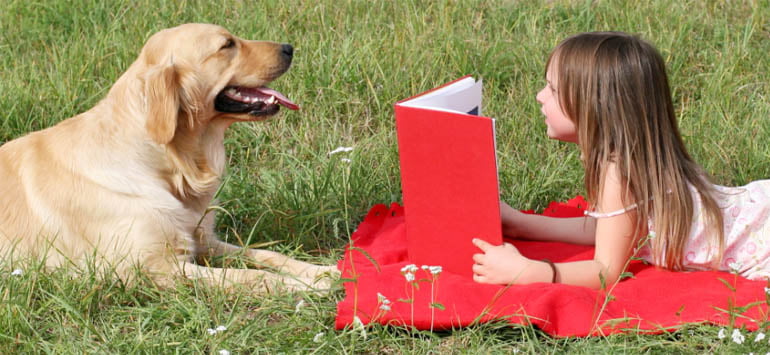 Young girl reading a book to a dog