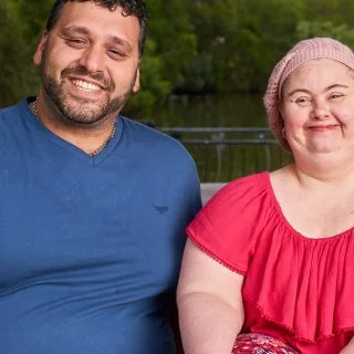 A Disability Support Worker sitting beside a lady with Down syndrome