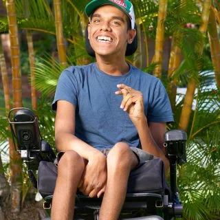 Man who uses a wheelchair outside in front of some trees
