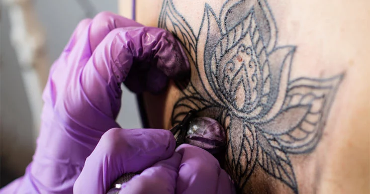 A person tattooing a lotus flower