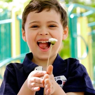 Boy with a disability holding a flower in a park