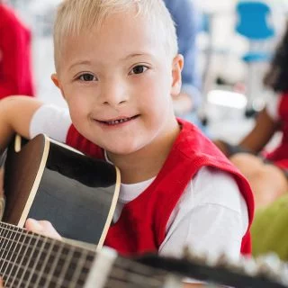 Young boy with a disability playing a guitar