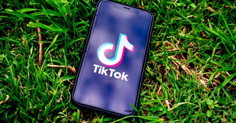 A mobile phone on the grass with the TikTok app on the screen