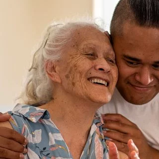 A man hugging an older women, both are smiling