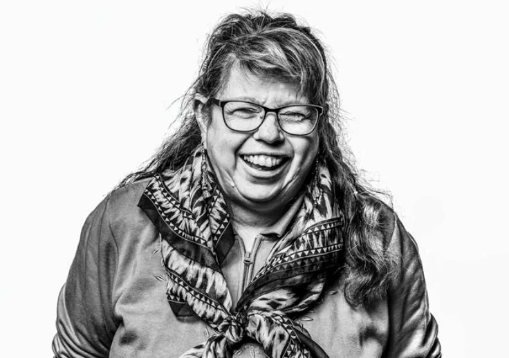 Erica Halverson, one of Aruma's Human Rights Advisors posing with a big smile on her face in a black and white photograph.