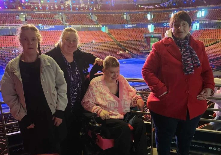 Aruma customers smiling at Disney on ice. They are standing in front of the ice rink.