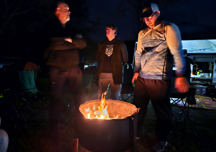 Aruma participants who attended Burleigh camp standing around the fire enjoying the light.